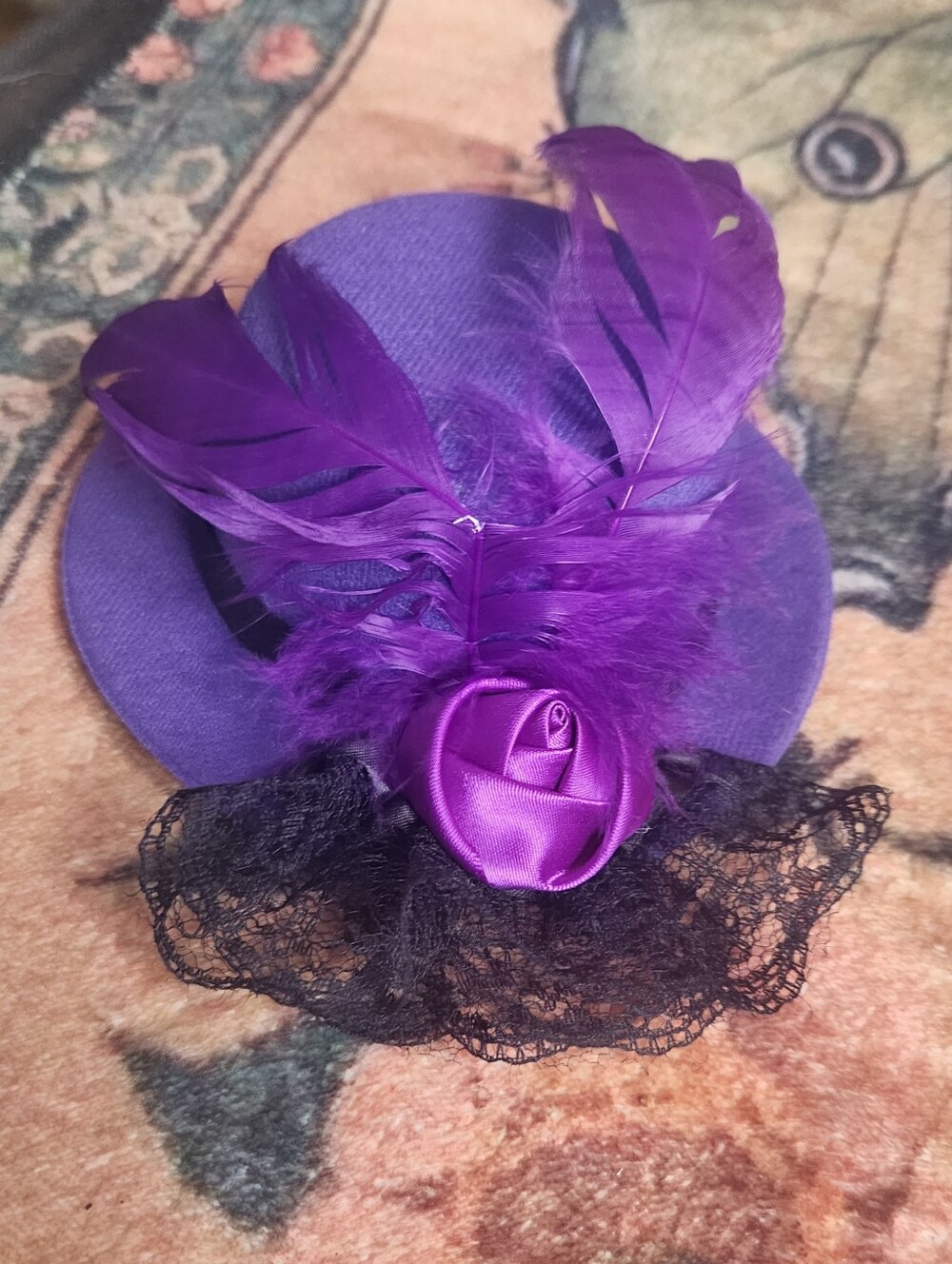 Purple mini hat fascinator hair clip adorned with vibrant matching feathers